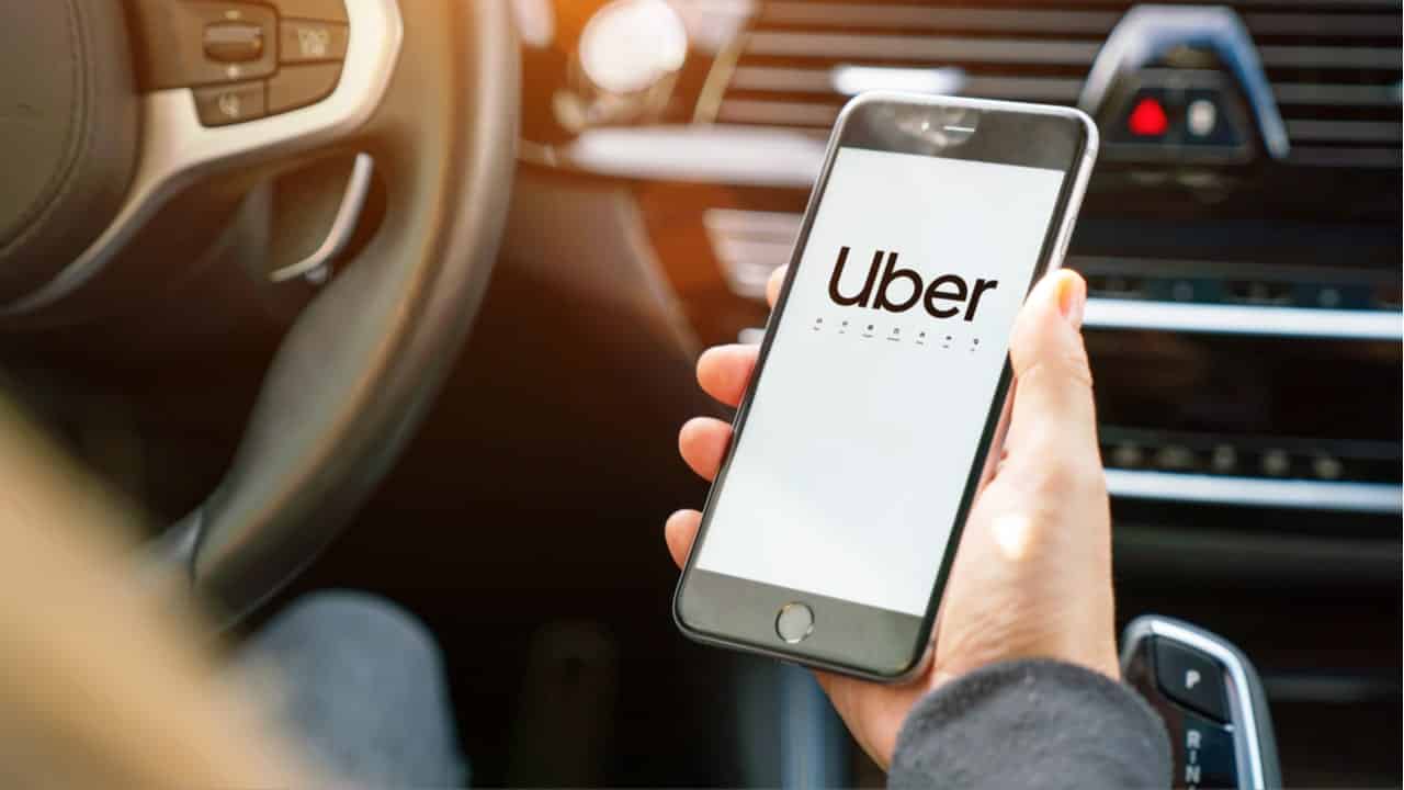 homem segurando celular com a tela aparecendo o aplicativo uber