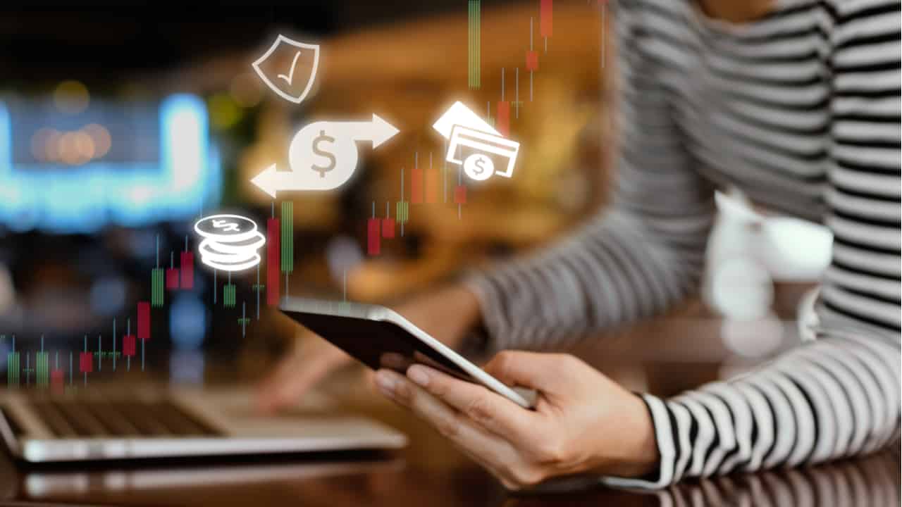A imagem mostra uma pessoa utilizando o celular e notebook. Acima do celular há imagens de transferências TED