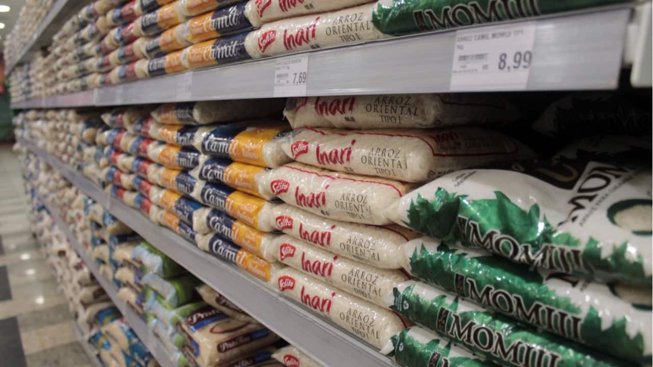 Alimentos como arroz e feijão na prateleira de um supermercado