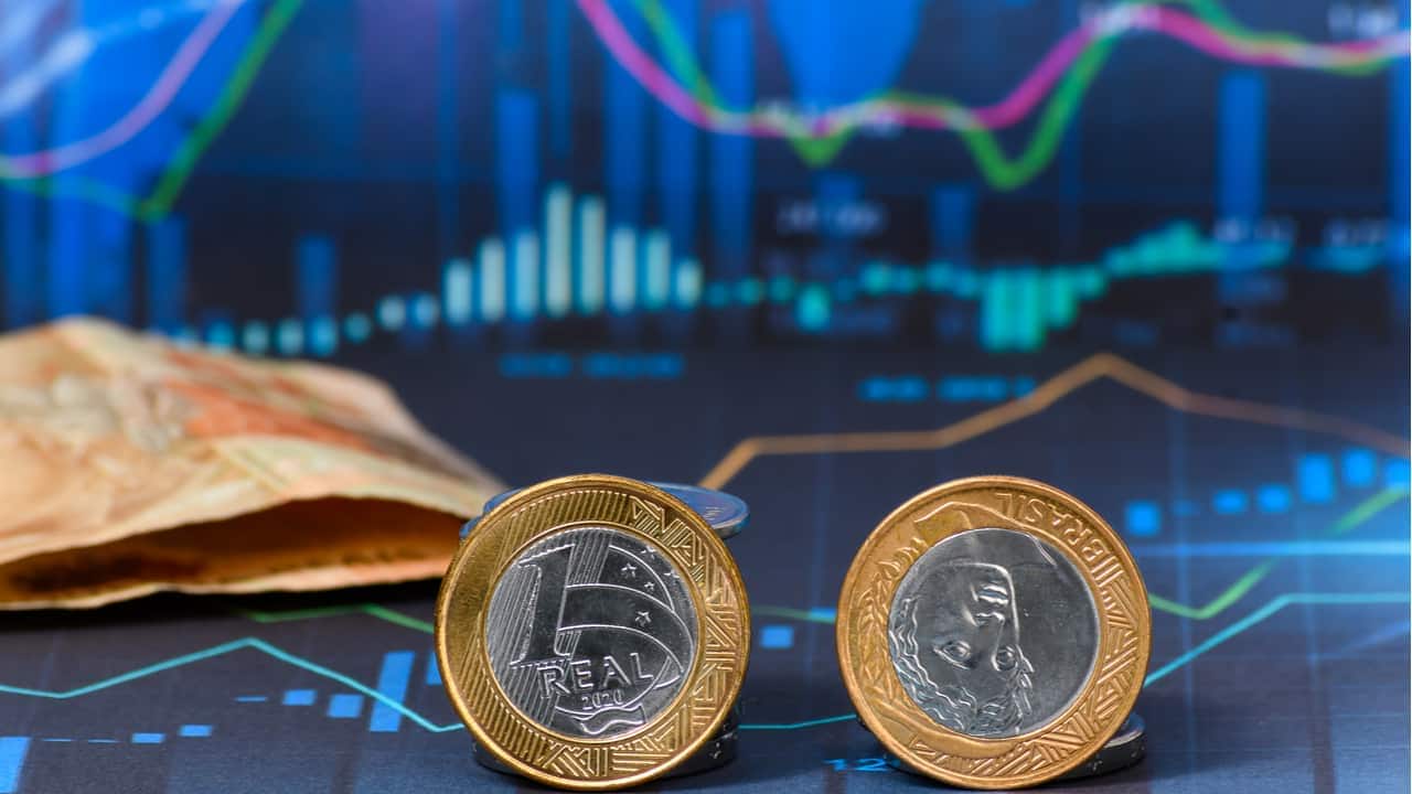 moedas e cédula de real em um fundo de ambiente digital