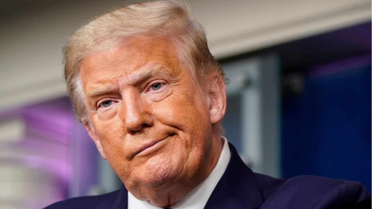 ex-presidente Donald Trump com expressão de insatisfação e ironia. Fundo desfocado.