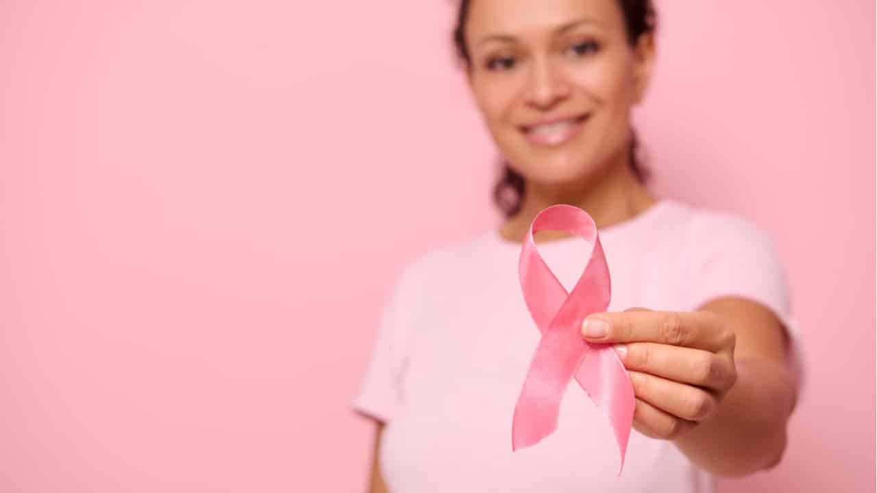 Mulher segurando o laço da campanha Outubro Rosa.