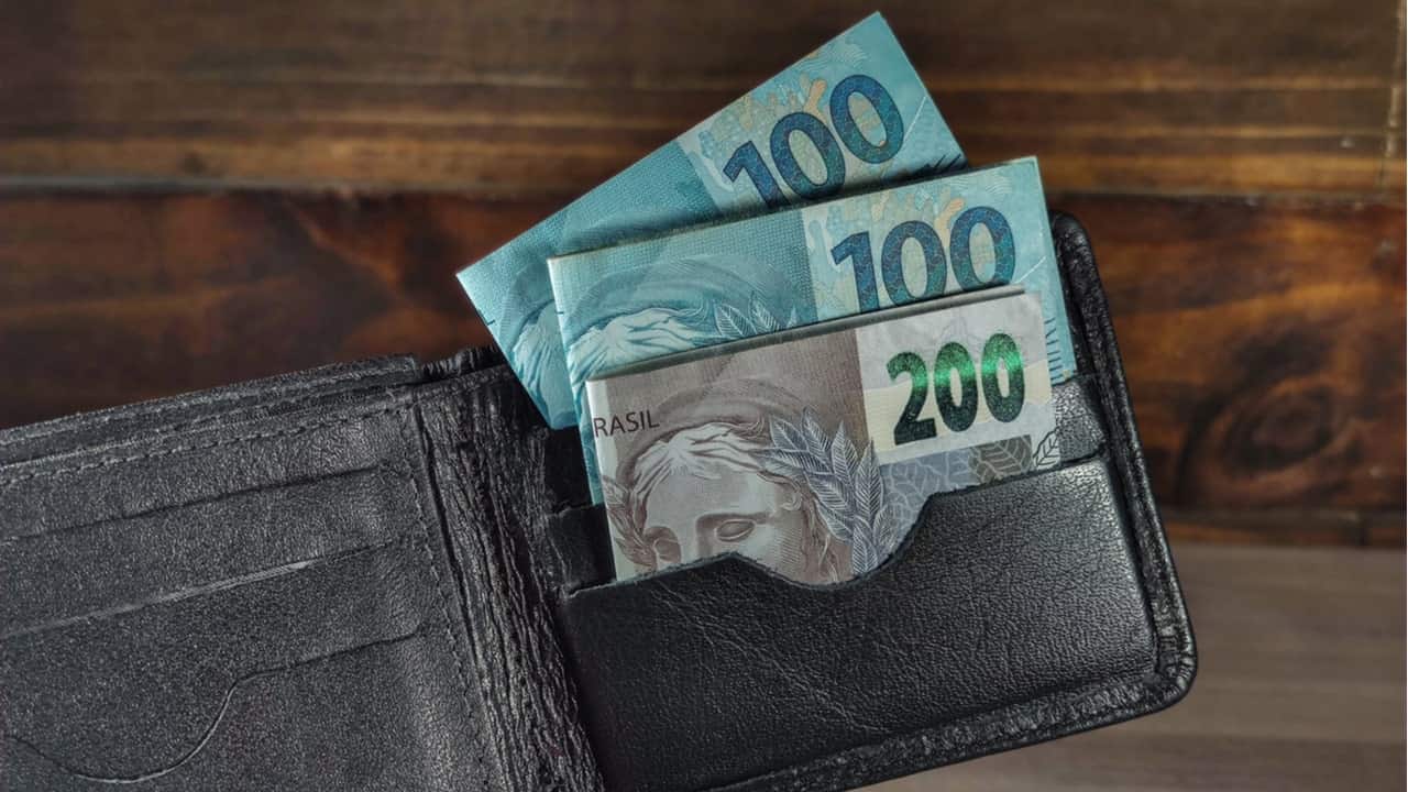 Uma carteira com notas de 100 e 200 reais à mostra