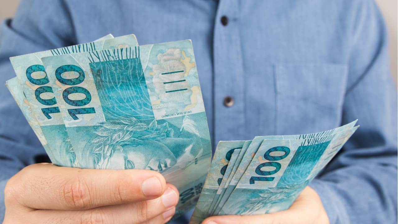 Pessoa segurando notas de 100 reais