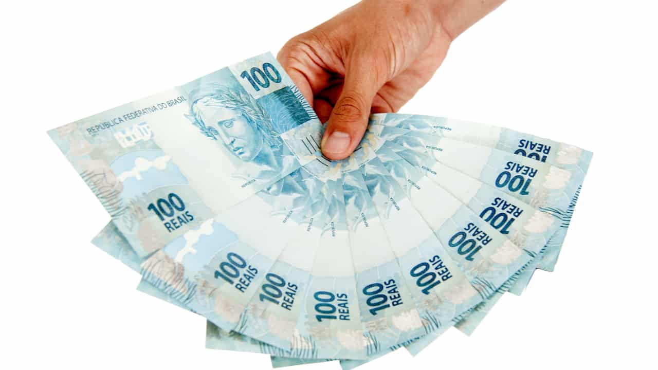 Mão segurando notas de 100