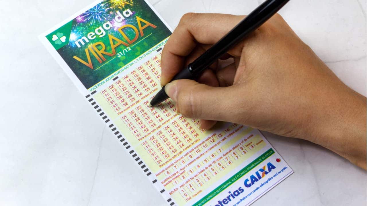 Mão marcando números no bilhete da Mega da Virada