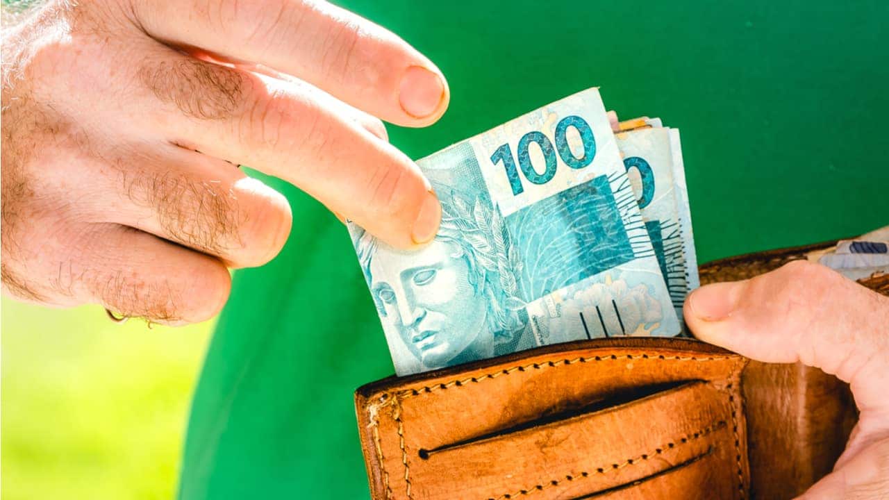 mãos tirando dinheiro de uma carteira.