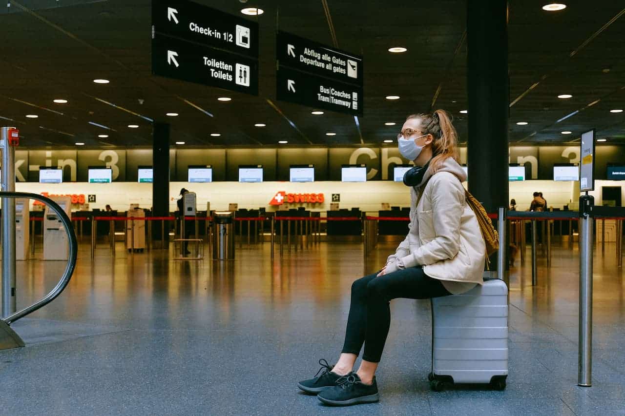 Foto de mulher sentada na mala dentro de aeroporto