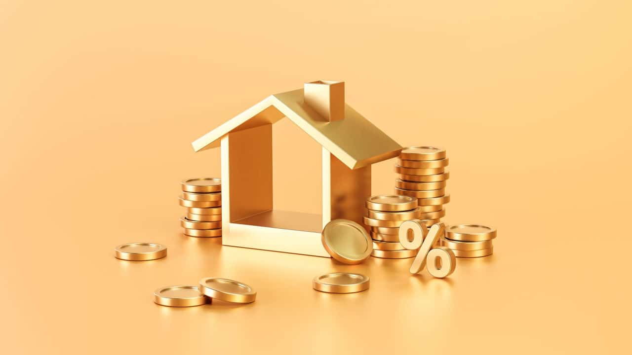 miniatura de uma casa e diversas moedas douradas empilhadas em cima da outra, representando seguro residencial