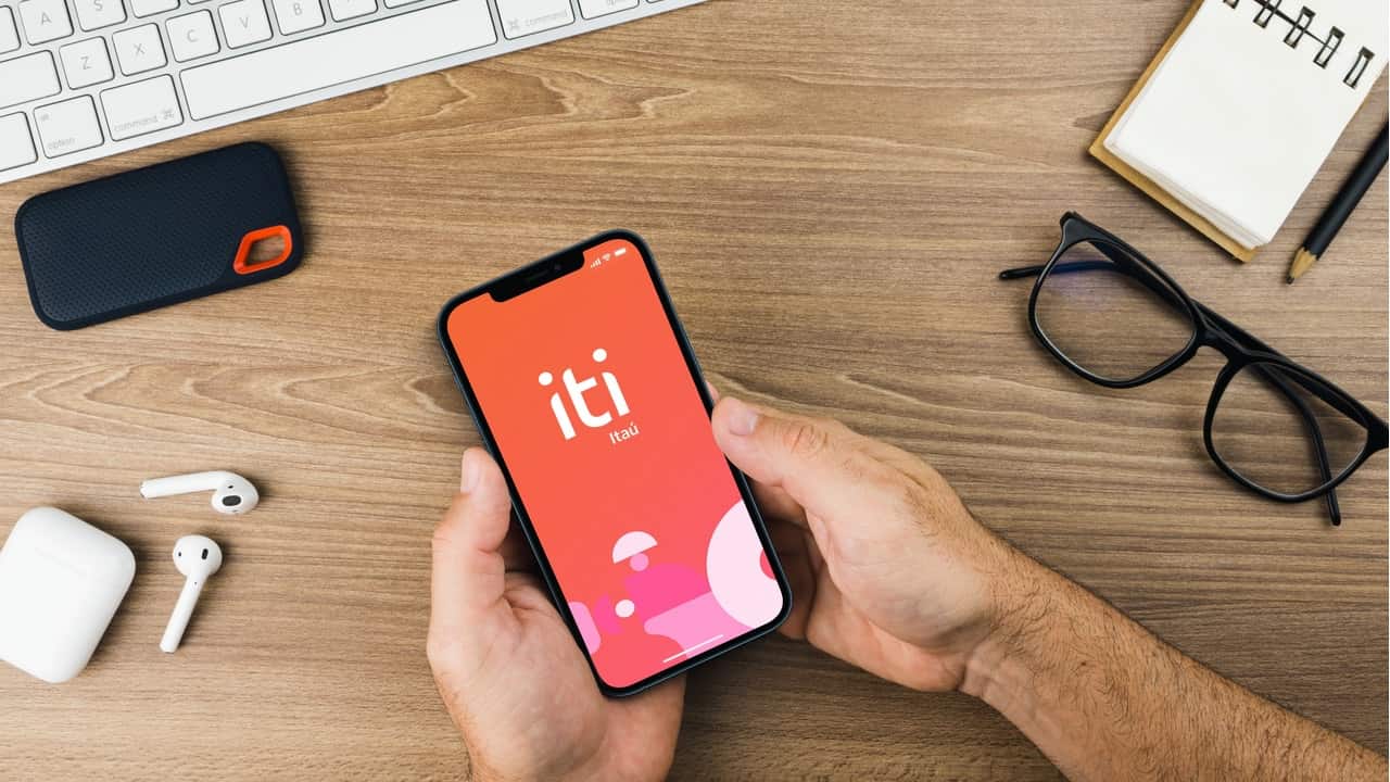 Mão segurando celular com print do aplicativo iti Itaú