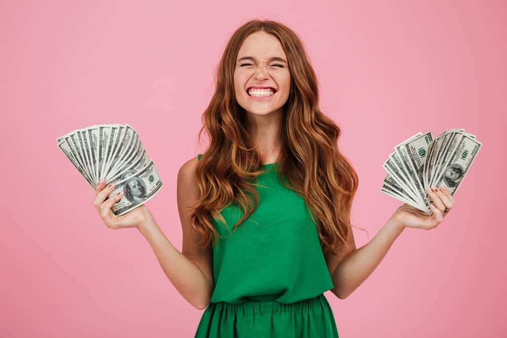 mulher sorrindo segurando várias notas de dólar