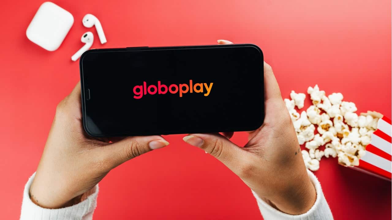 celular sendo segurado por uma pessoa, com aplicativo do globoplay aperto