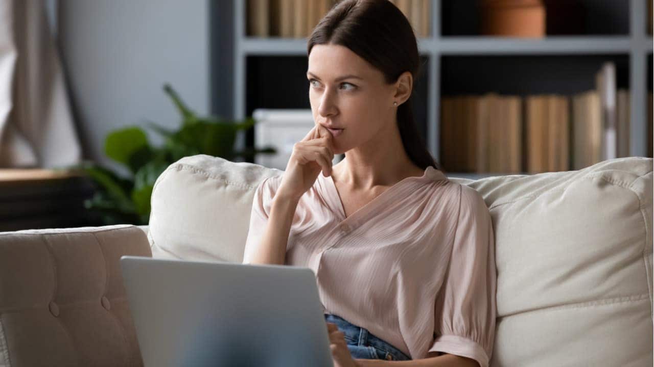 Mulher pensativa com notebook no colo após sinais de Internet no Brasil seremdesligados