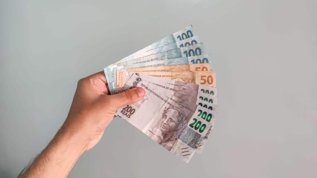 Mão segurando várias notas de dinheiro