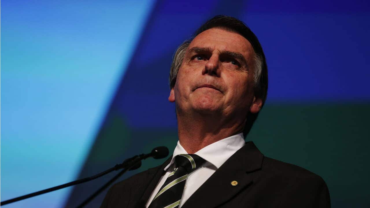 Bolsonaro em frente a um microfone com expressão séria