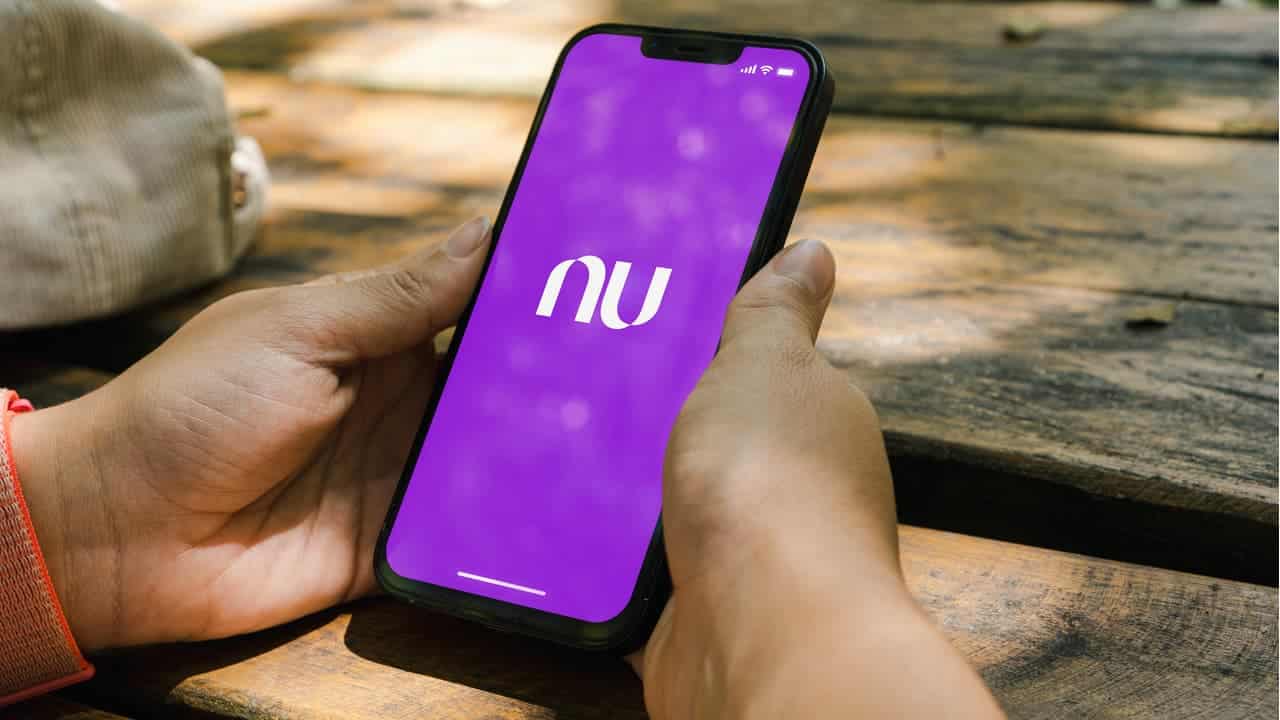 Mãos segurando um celular com aplicativo do Nubank na tela