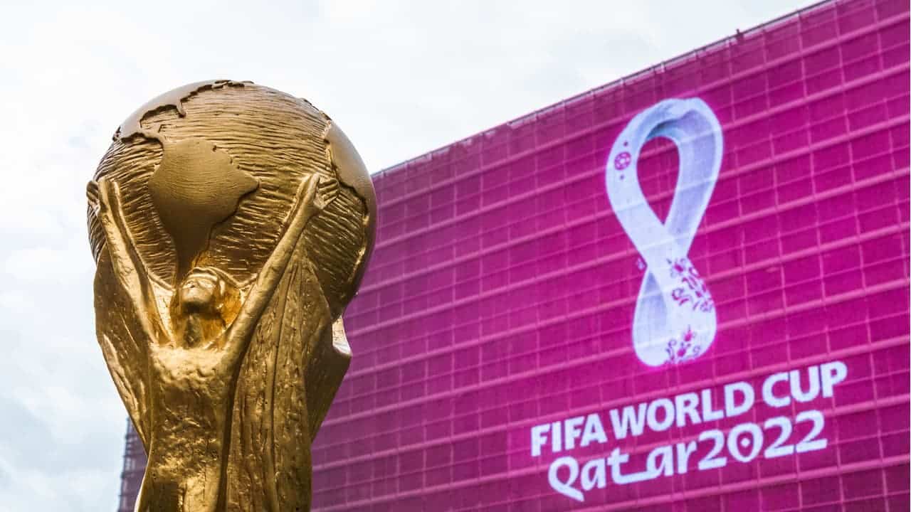 Troféu da Copa em frente a um painel com logo da Copa do Mundo 2022 no Catar