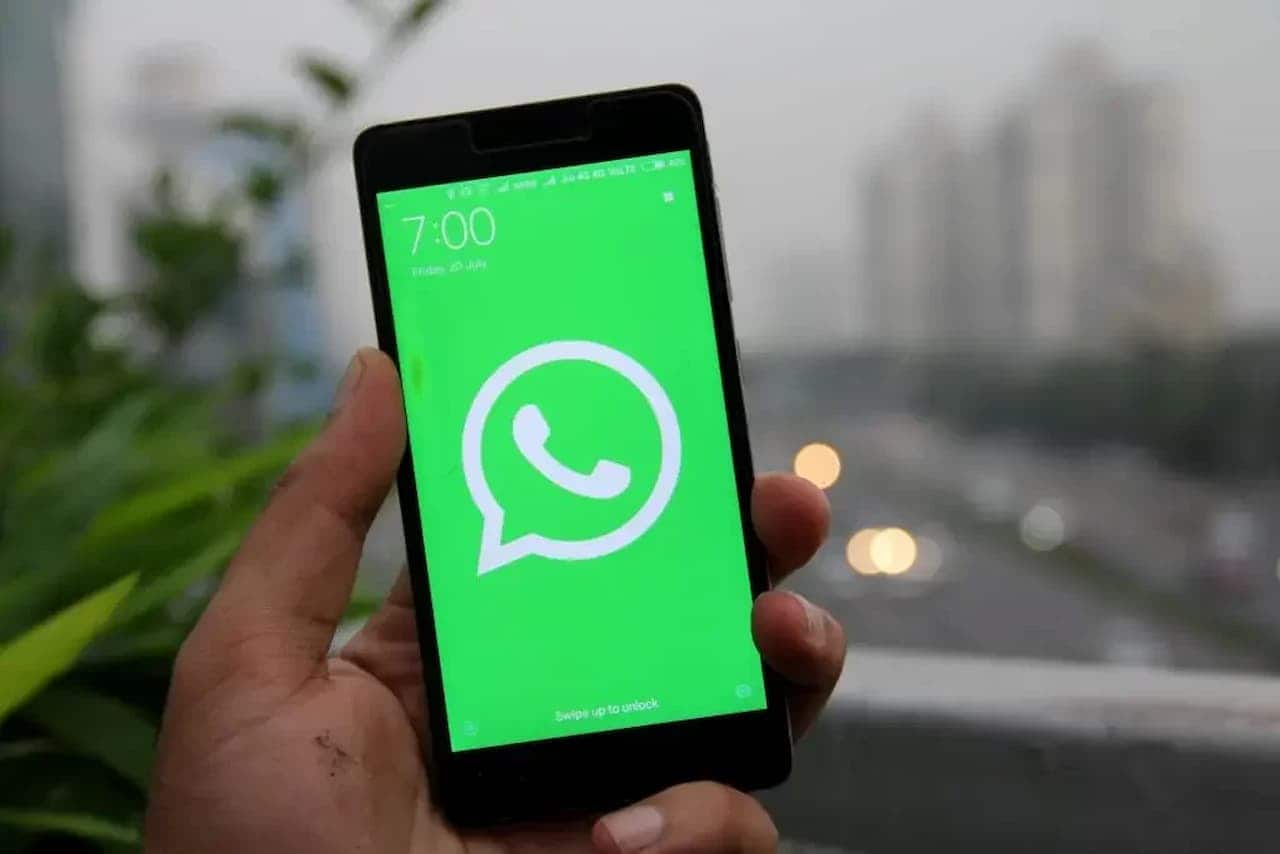 Mão segurando celular com foto do WhatsApp