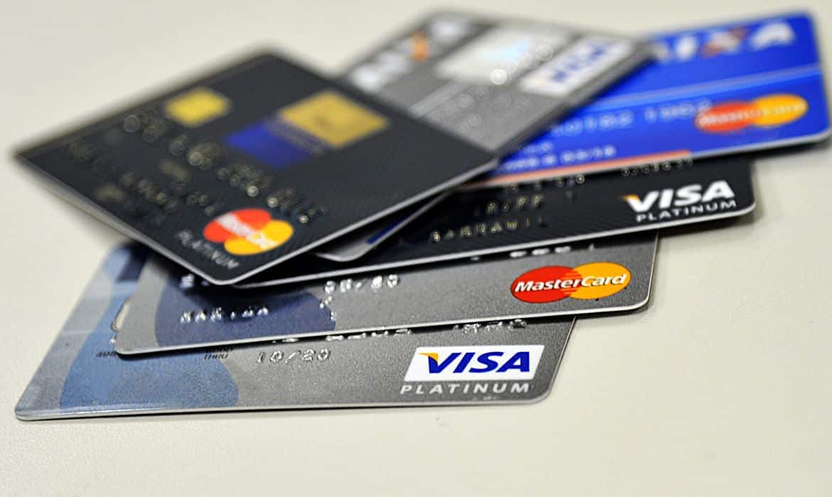 Vários cartões de crédito empilhados sobre uma superfície cinza