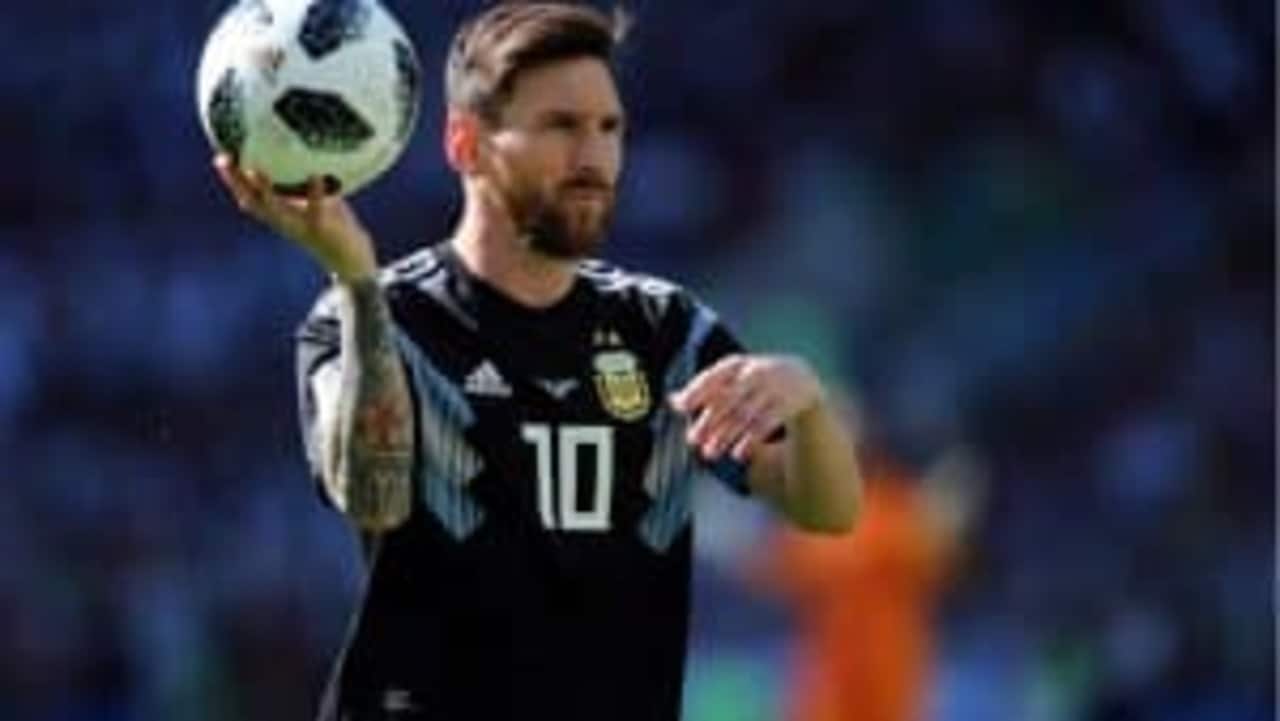 jogador Messi segurando uma bola de futebol