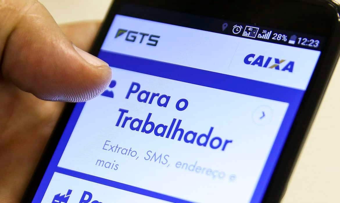 Mão mexendo no celular no aplicativo do FGTS