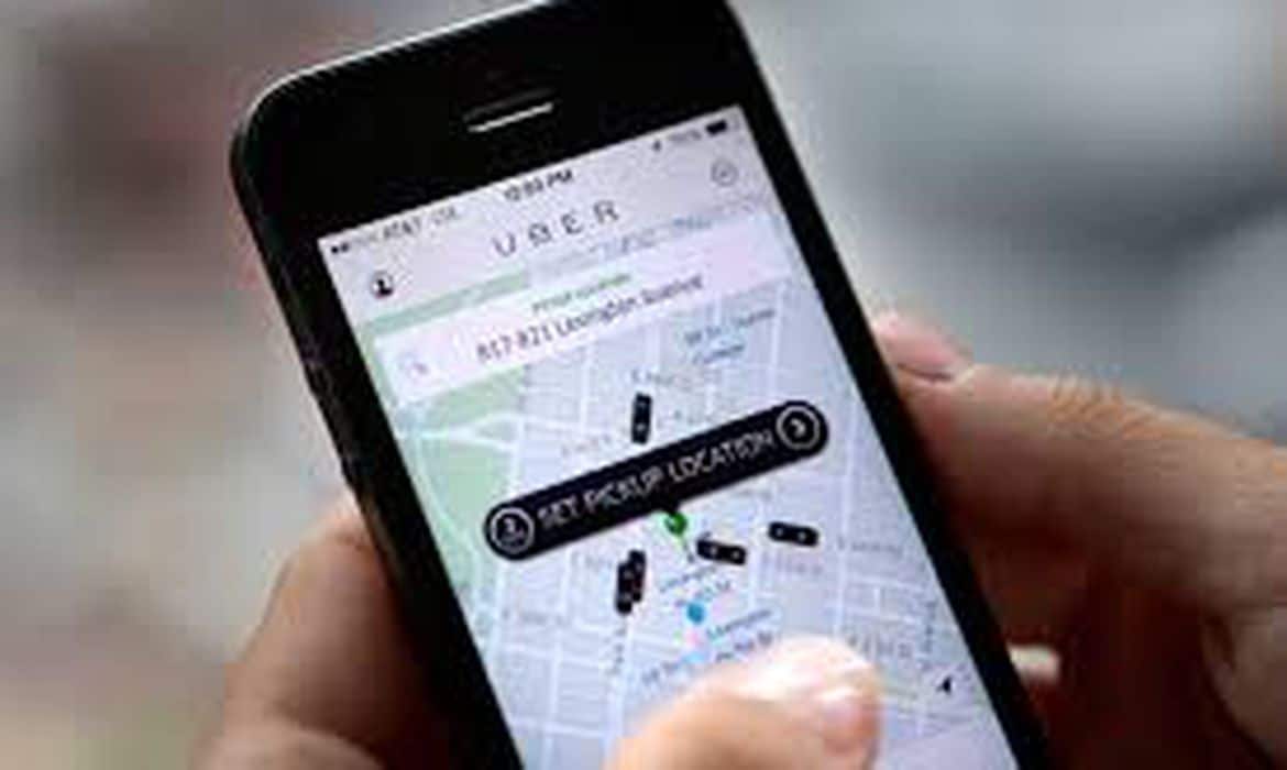 Mãos segurando o celular aberto no aplicativo da Uber