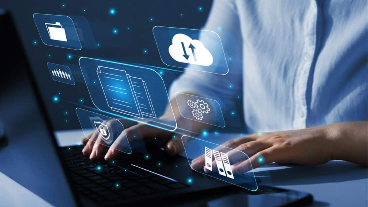 Pessoa usando computador com acesso à internet e ícones do universo digital saltando da tela