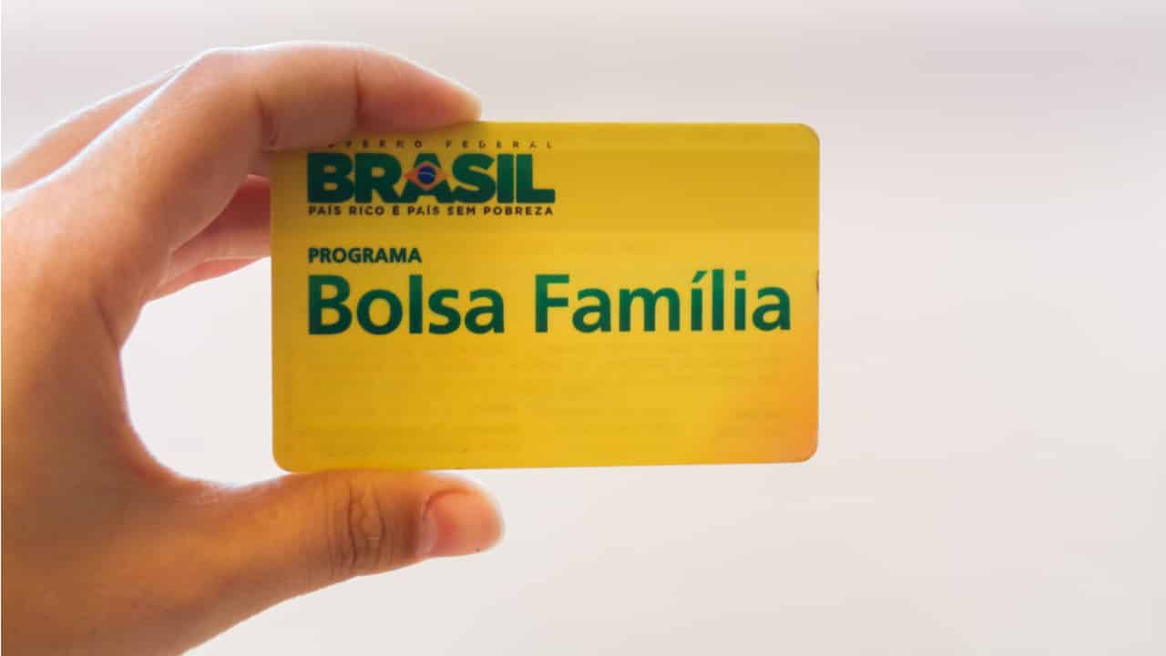 Mão segurando cartão do Bolsa Família