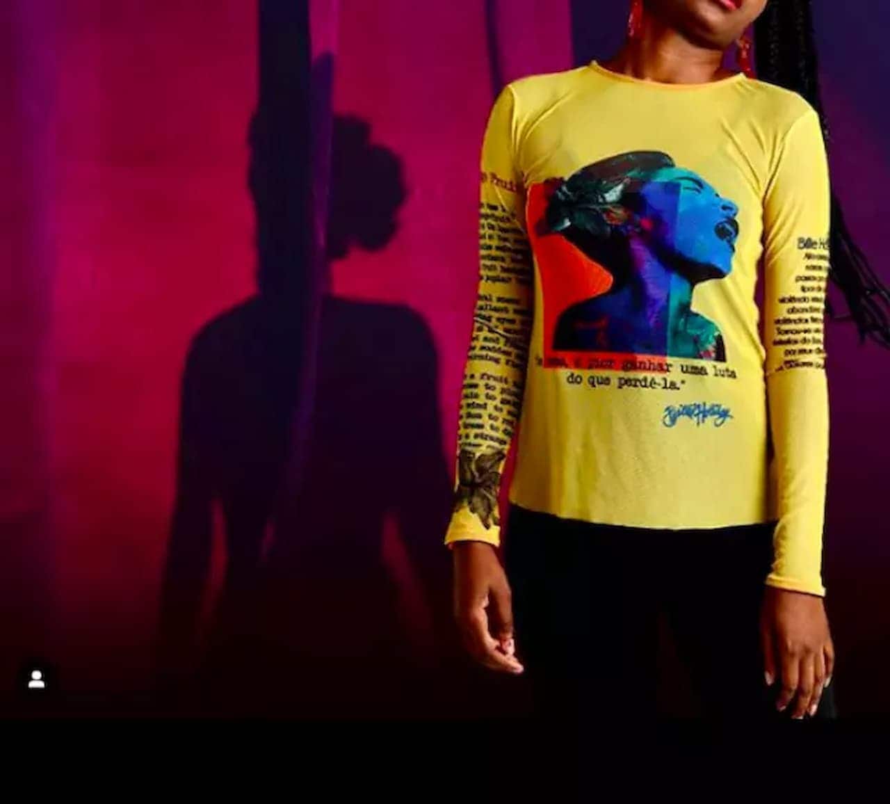 Imagem de editorial de moda. Na foto aparece no canto direito uma mulher em pé vestindo uma camisa amarela de mangas compridas. O rosto da mulher não está enquadrado