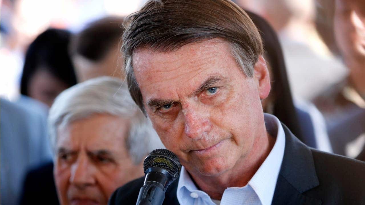 imagem do ex-presidente, Jair Bolsonaro, com uma expressão séria frente a um microfone