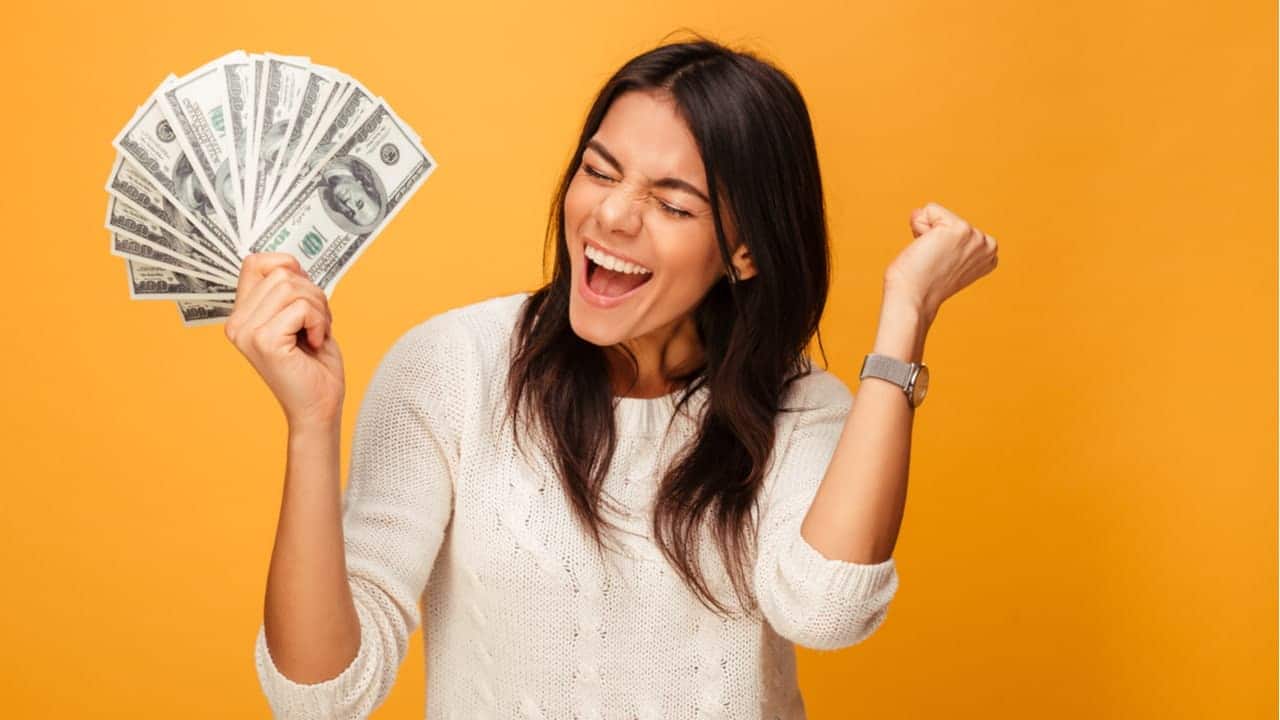 Imagem de mulher feliz comemorando com dinheiro em uma das mãos