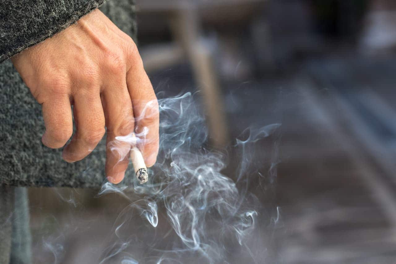 Homem com cigarro queimado na mão
