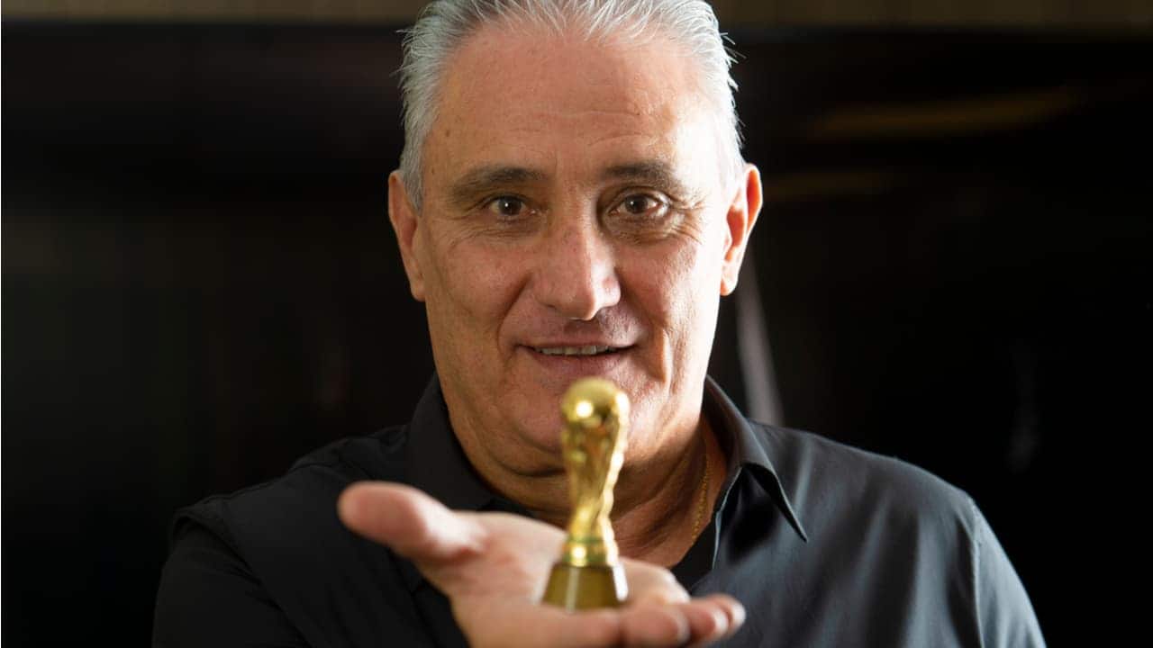 Tite segura em uma das mãos uma miniatura do troféu da Copa do Mundo