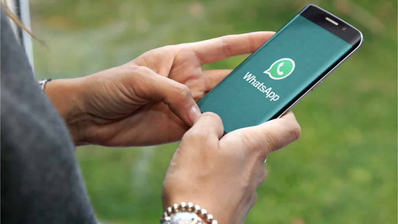 Pessoa segurando celular com a tela exibindo o WhatsApp