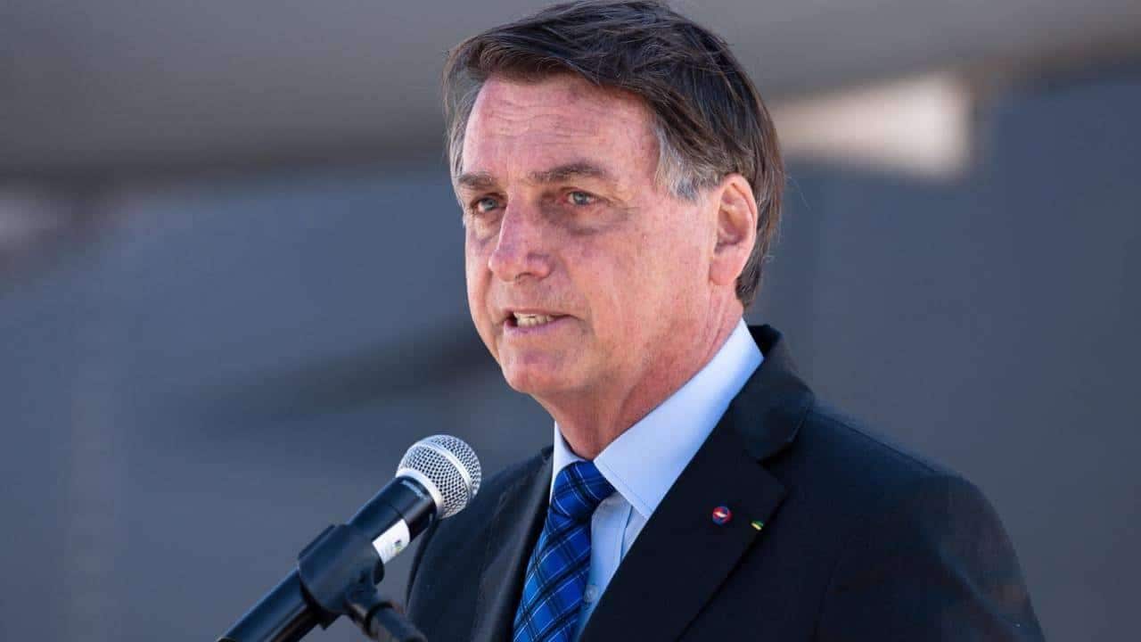 Imagem do ex-presidente Jair Messias Bolsonaro em frente a um microfone, discursando