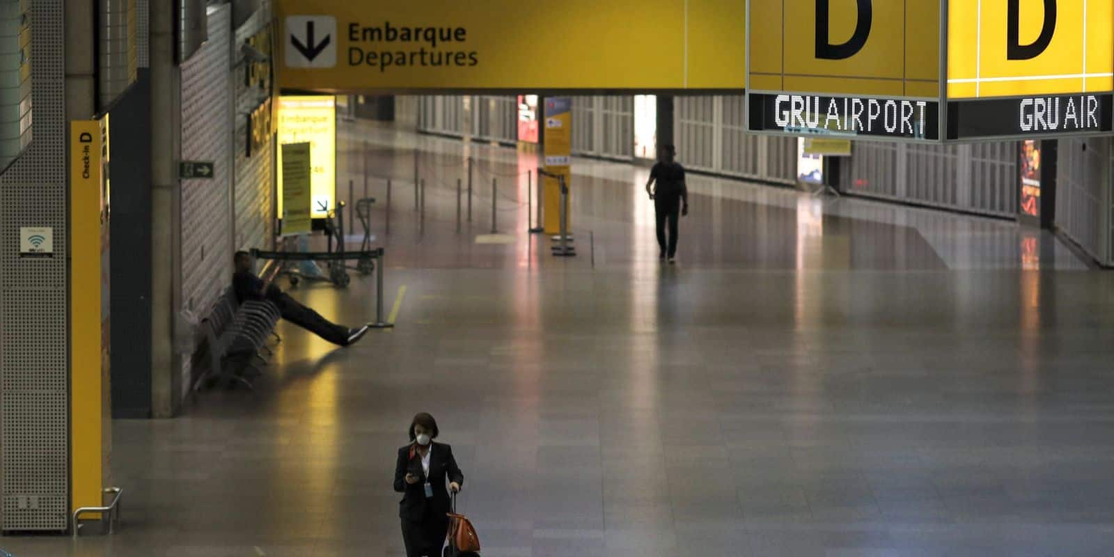 Comissária caminha no aeroporto vazio