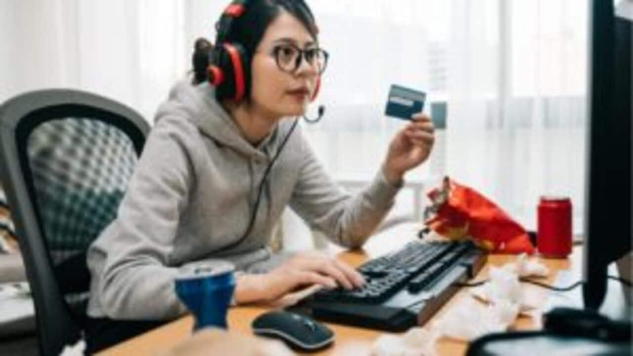 Mulher com fone de games segurando cartão