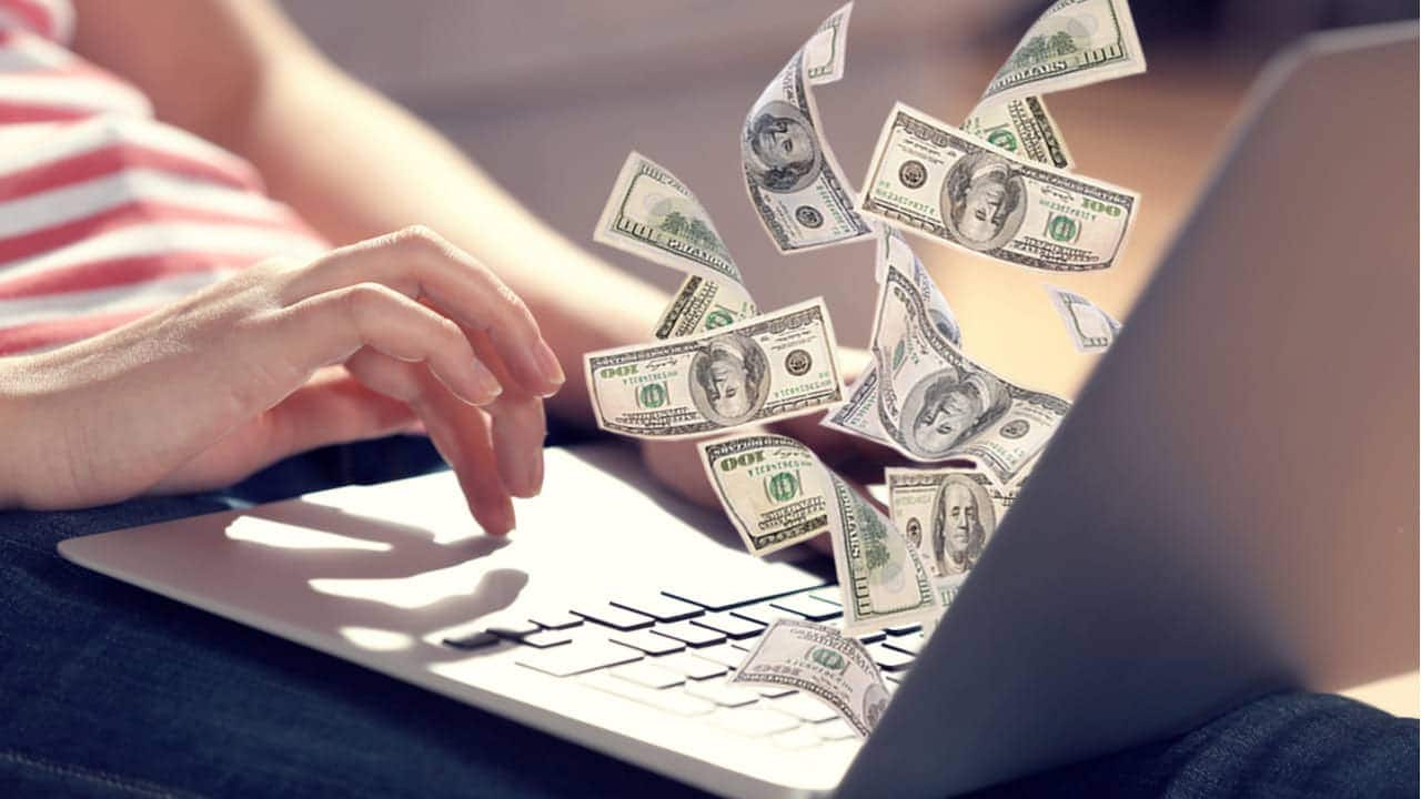 Notas de dólar saindo da tela de um computador