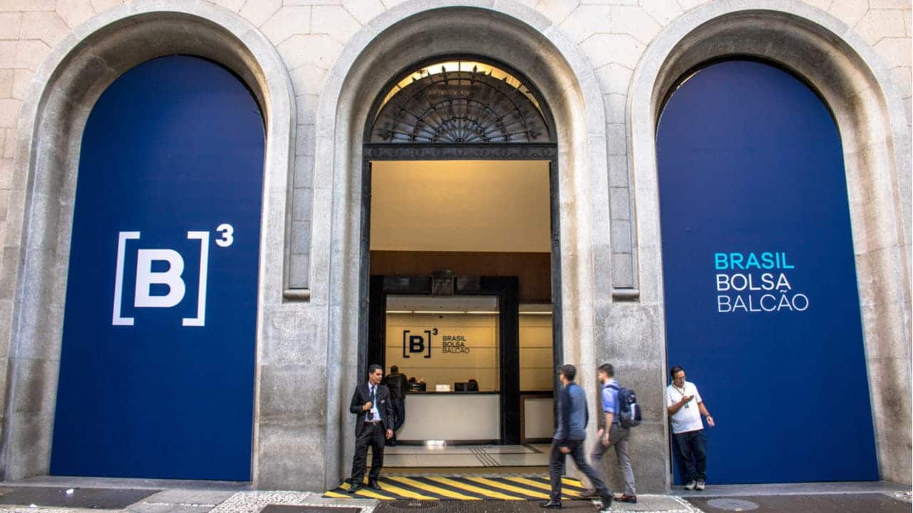 Entrada da sede da B3, Bolsa de Valores brasileira, com quatro pessoas na frente