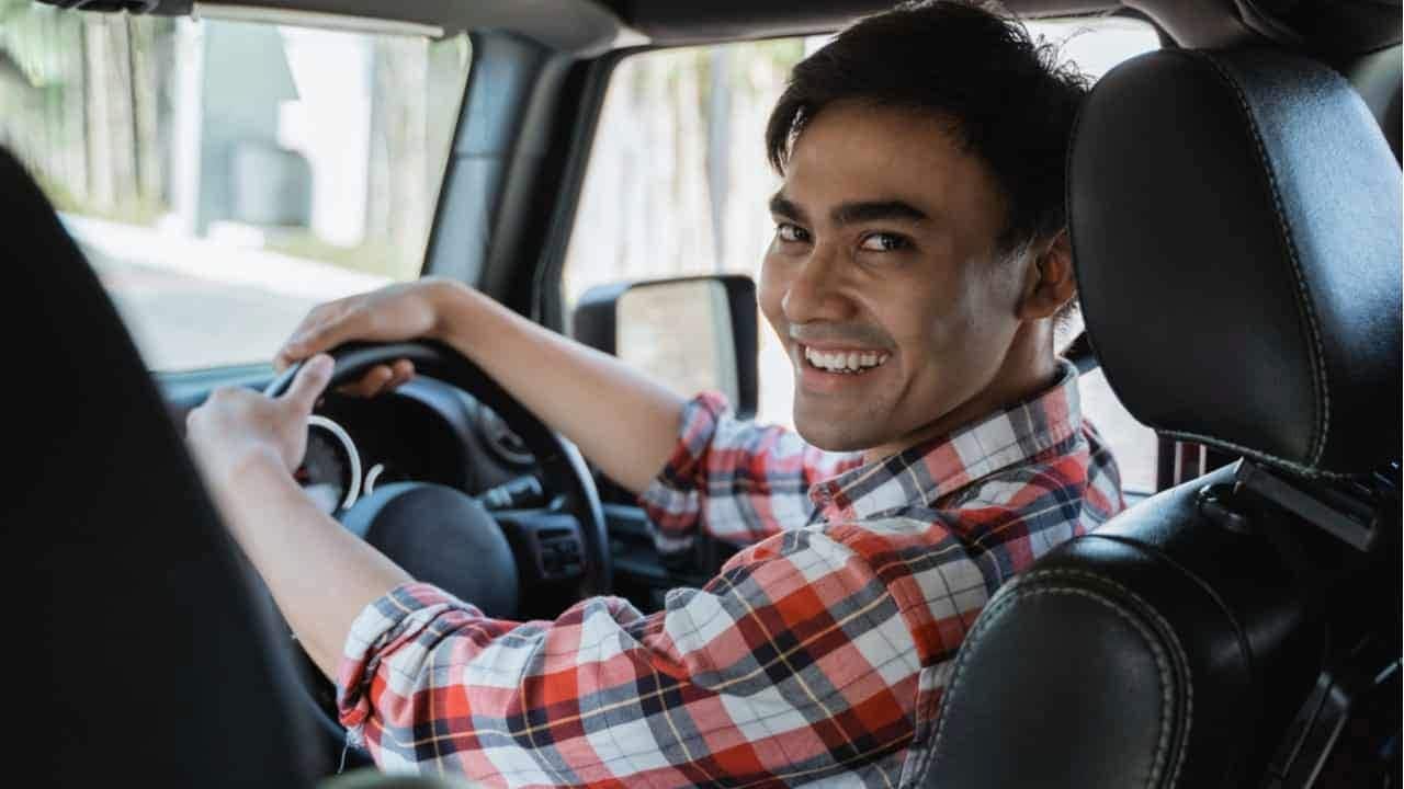 Motorista de carro sorrindo para a câmera