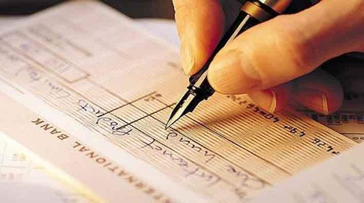 pessoa assinado e preenchendo uma folha de talão de cheques