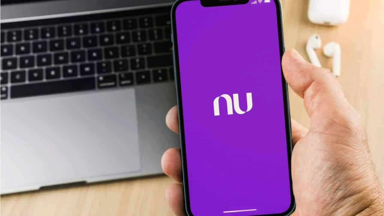 Pessoa segurando celular que exibe logo do Nubank