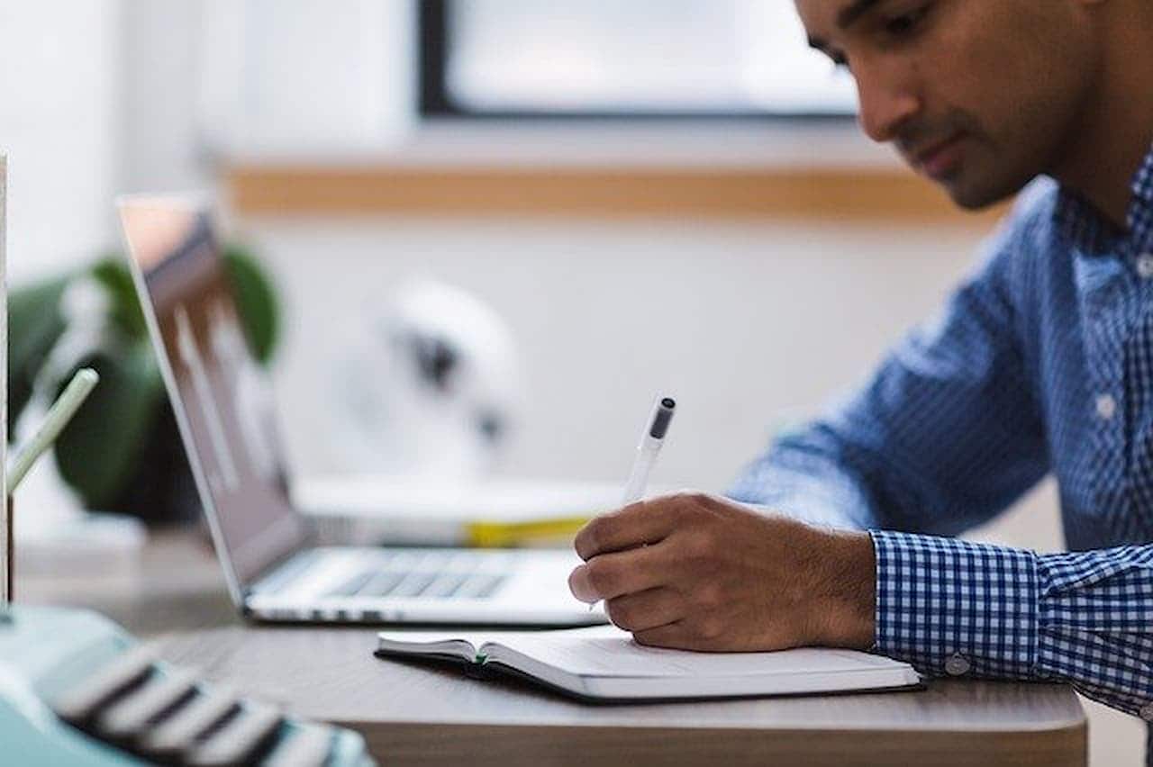 Homem com caderno notebook aberto escrevendo em seu caderno