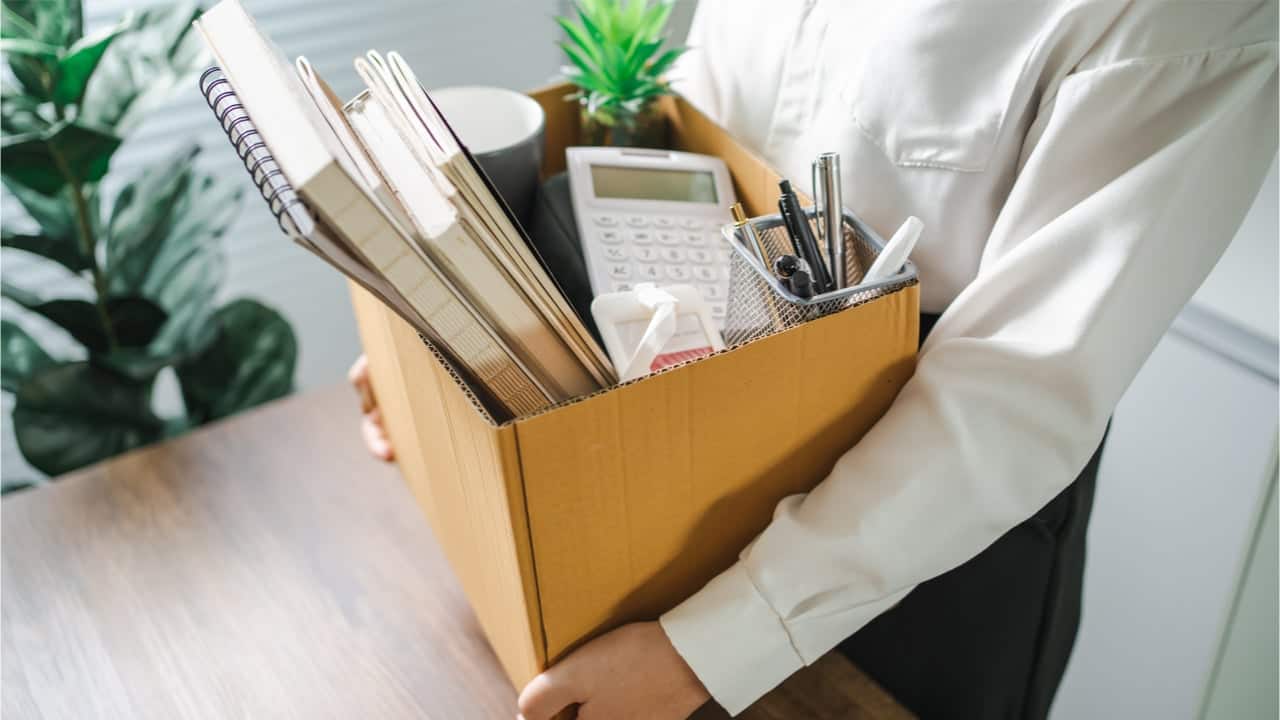 Pessoa carregando caixa com pertences em uma empresa