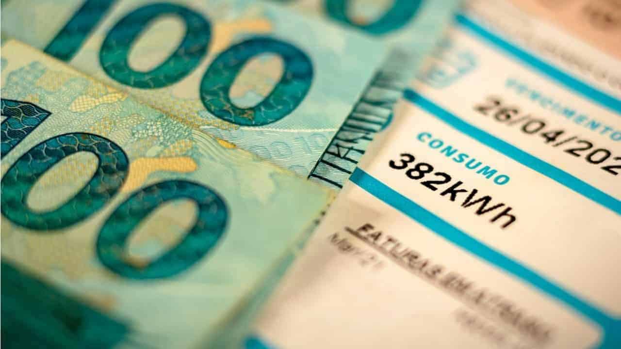 Conta de luz ao lado de notas de 100 reais