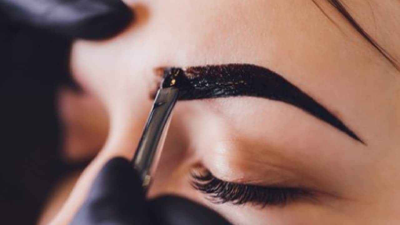 imagem de designer de sobrancelha fazendo henna de tinta em cliente