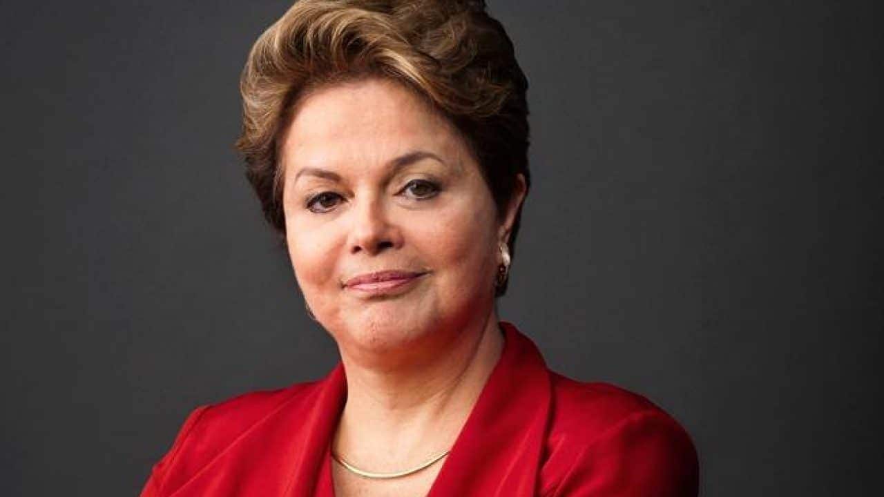 Ex-presidenta Dilma Roussef vestindo vermelho e sorrindo para a câmera