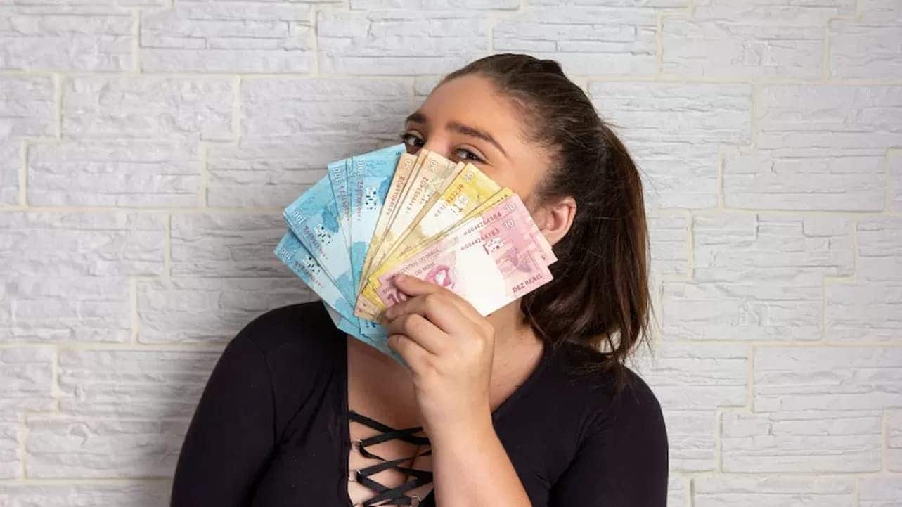 Mulher com leque de notas de reais