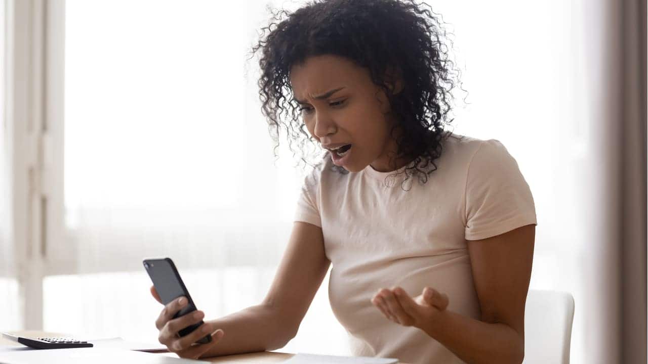 Mulher com expressão de choque olhando para tela de celular