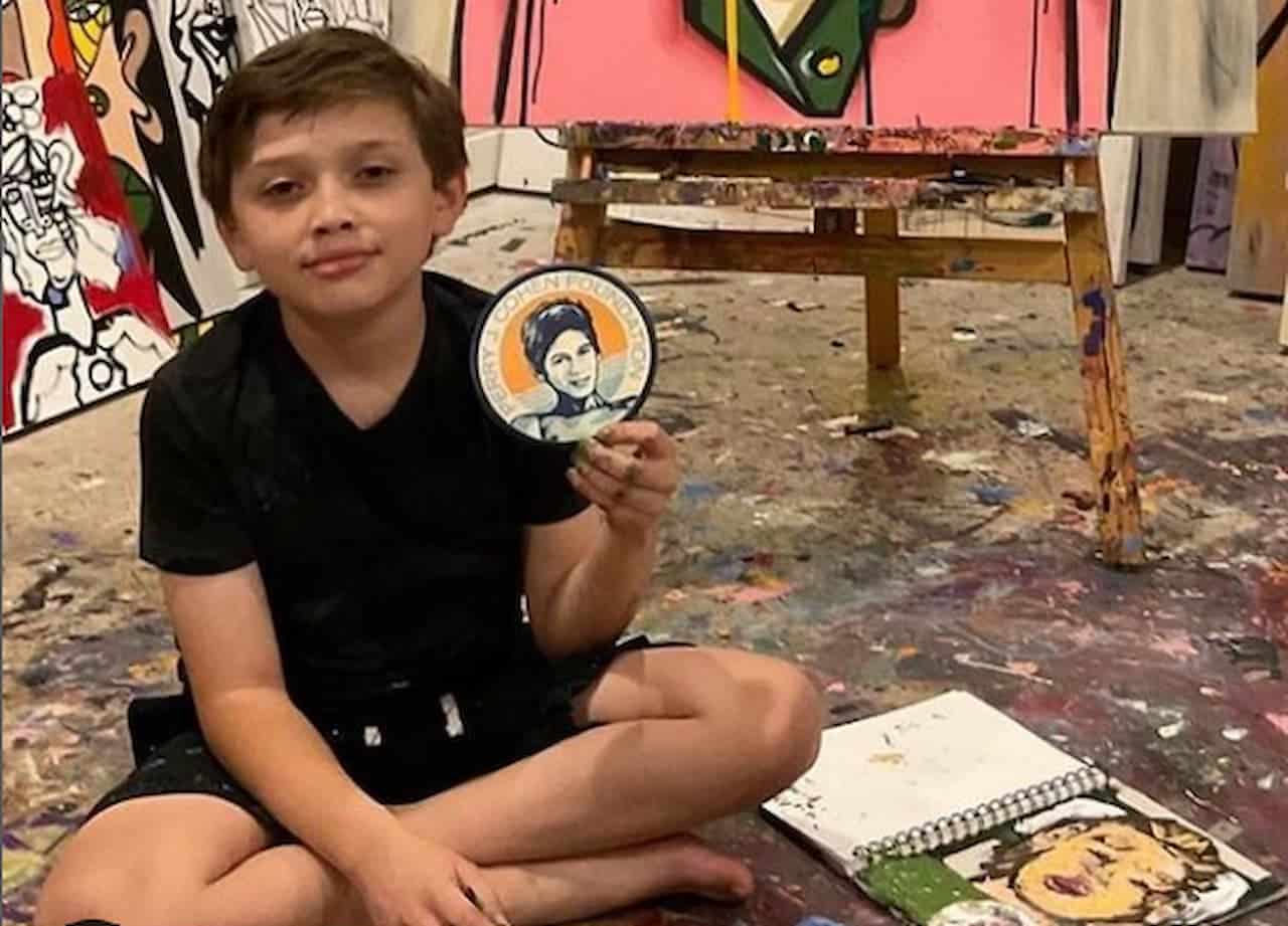 Andres Valencia sentado, com suas obras ao redor